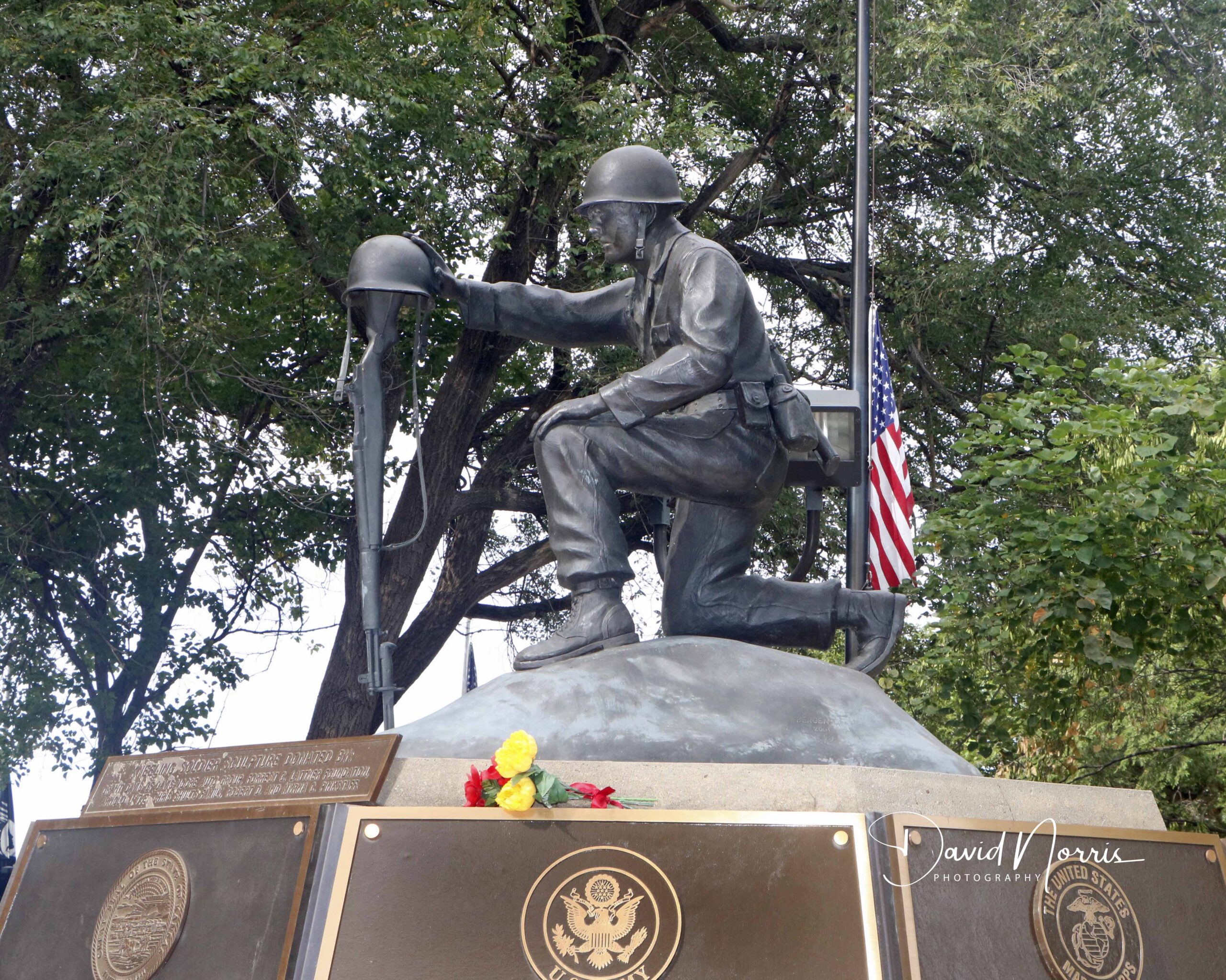 Soldier statue with American flag and plaques.