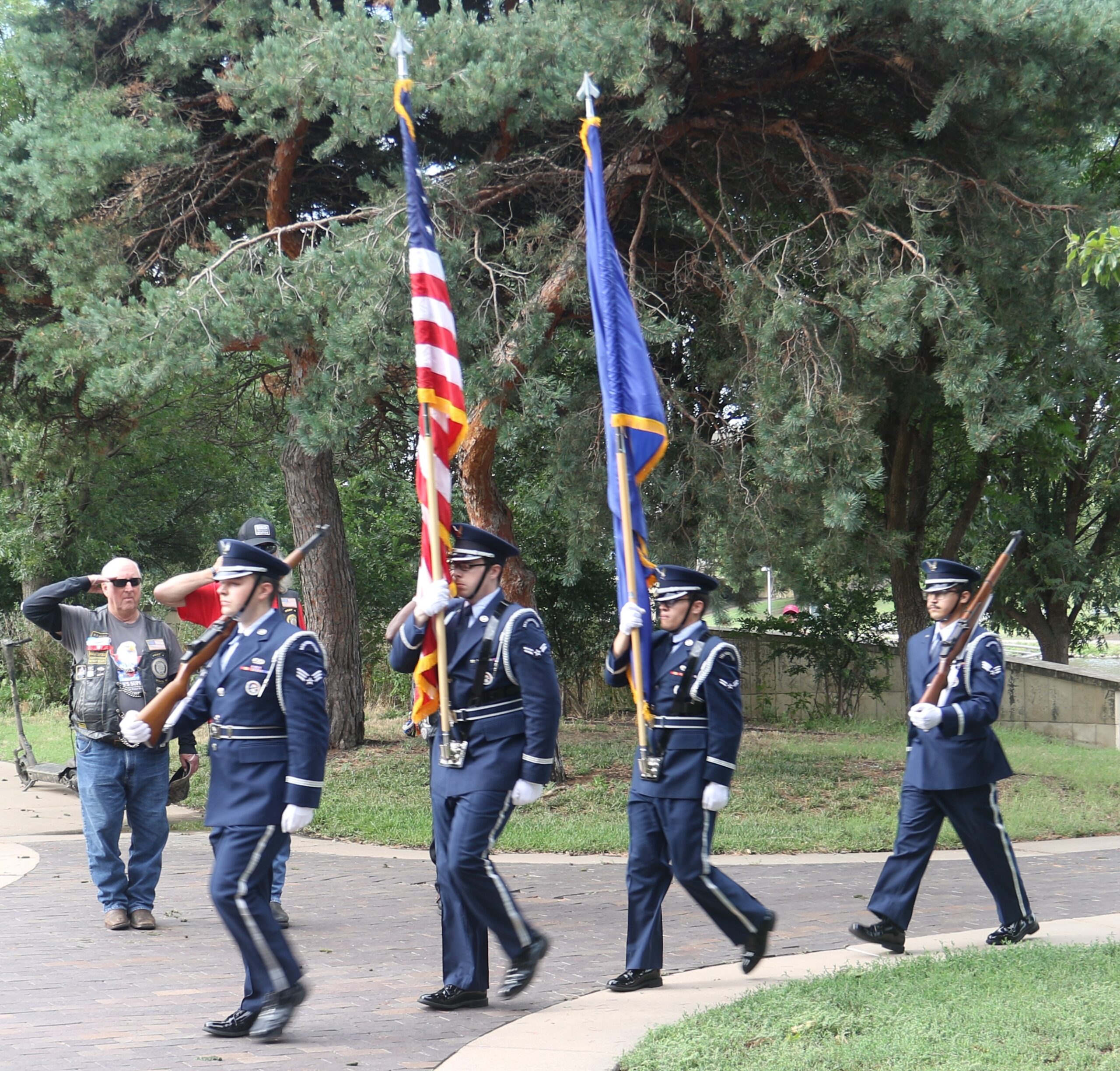Honor guard marching with flags in park.